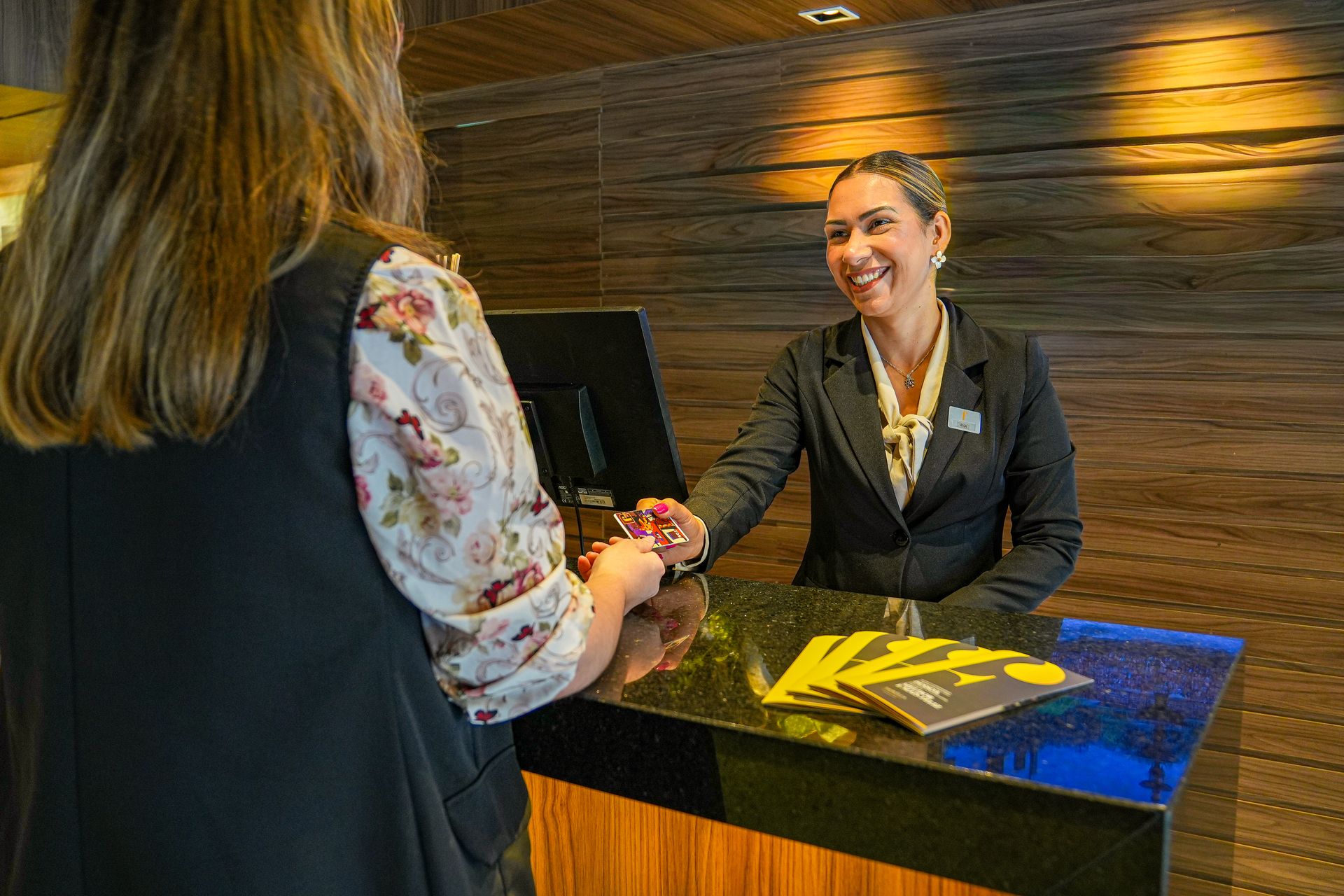 Recepcionista entrega um cartão-chave a uma hóspede