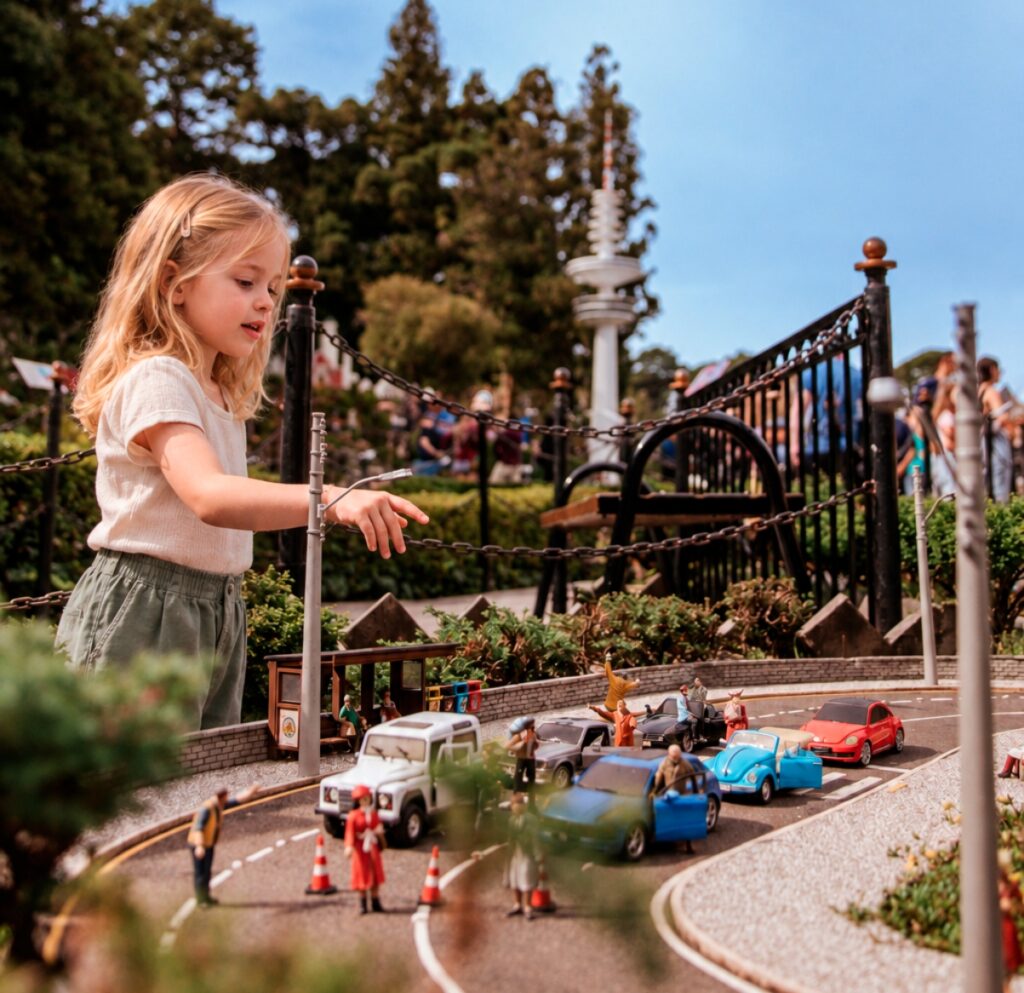 Menina observando uma cidade em miniatura durante um passeio em Gramado